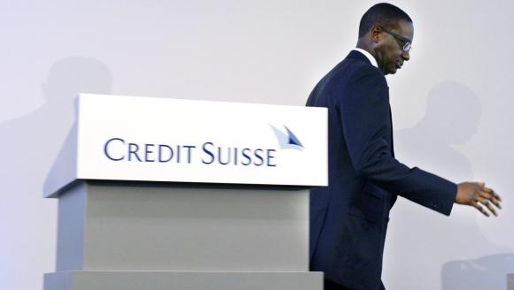 Uomo di colore, in abito formale, si allontana da un pulpito con la scritta Credit Suisse