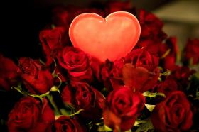 Un cuore luminoso in mezzo a un mazzo di rose rosse.
