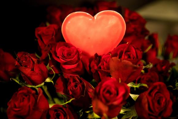 Un cuore luminoso in mezzo a un mazzo di rose rosse.