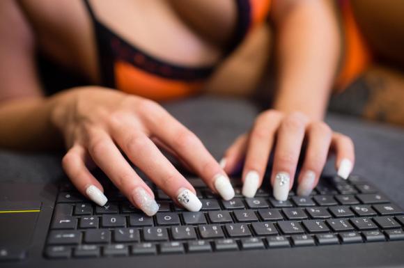 Una donna mezza nuda con le mani su una tastiera di computer