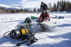 Un giovane sta per immergersi nel lago gelato con una tuta spaziale