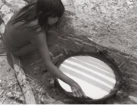 Une femme retourne une galette de manioc