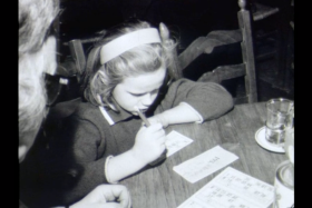 Una bambina segna con una matita i numeri estratti su una cartella da tombola a un tavolino da bar