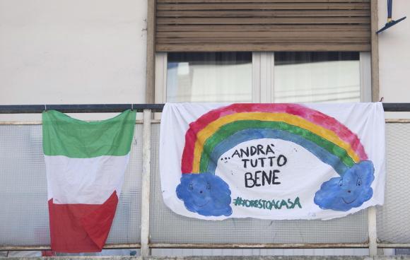 Distasi su un balcone la bandiera italiana e un lenzuolo con scritto andrà tutto bene.
