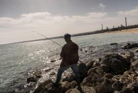 Pescatore ad Augusta (Sicilia) con sfondo di fabbrica.