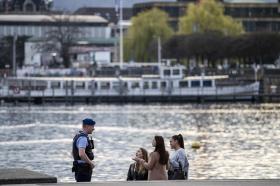 un poliziotto parla a tre ragazze in riva al lago.