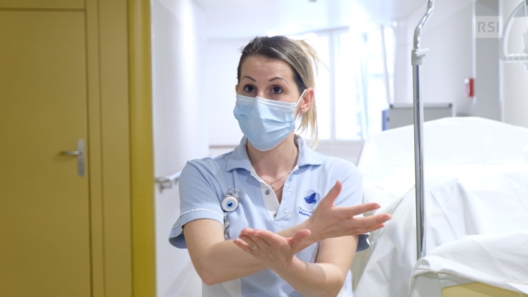 Un infermiera con mascherina in una camera d ospedale spiega qualcosa indicando con le mani