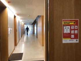 Blick in einen Korridor, rechts an der Wand ein rotes Plakat mit Hygiene-Vorschriften.