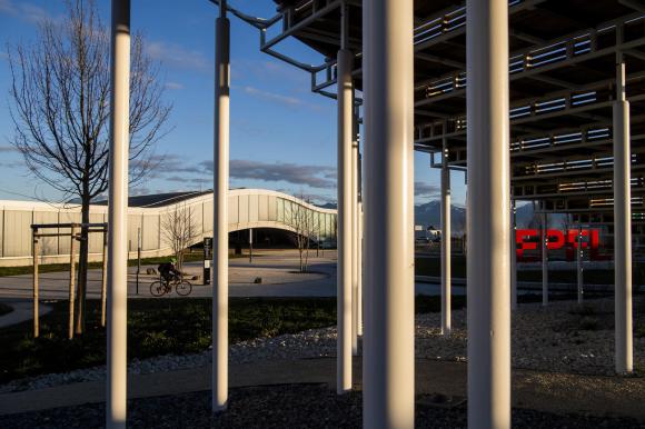 Edificio a forma ondulata circondato da un parco con l effige EPFL; in primo piano, piloni d acciao