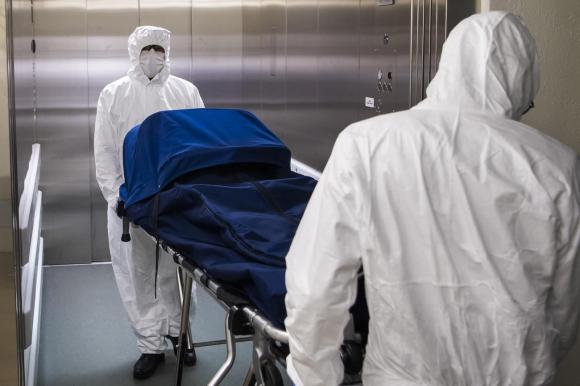 Due impiegati delle pompe funebri portano via una vittima del covid-19 dall ospedale di Losanna.