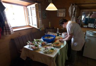 The hut ward assistant prepares salad for the guests in the kitchen of the Saseo mountain hut.