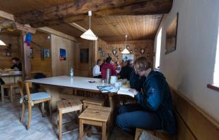 Guests sitting and relaxing in the recreation room of the Saoseo mountain hut.