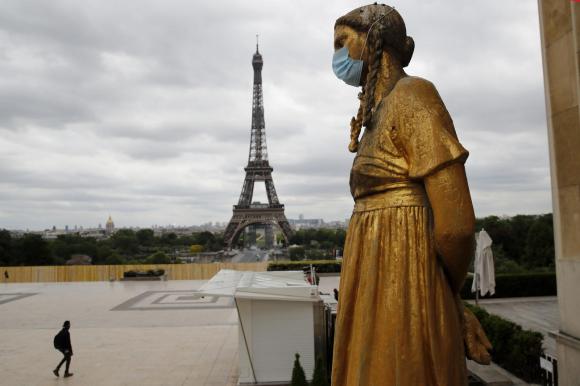 La torre Eiffel vista dal Trocadero, dove una statua femminile indossa una mascherina chirurgica.