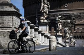 Un uomo in bicicletta a Roma con la mascherina. Dietro Castel Sant Angelo.