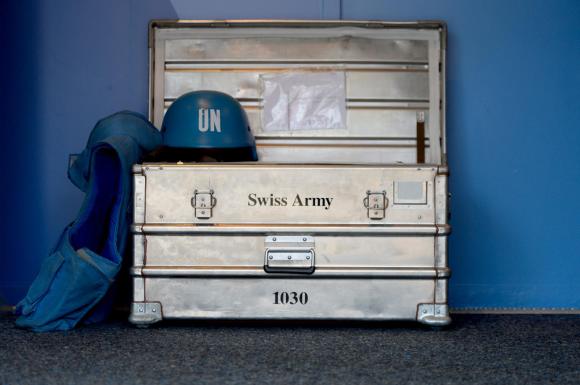 Ein blauer Helm und ein blaues Gilet auf einer silbernen Kiste vor einer blauen Wand.