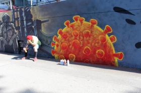Giovane seduto davanti a un murales raffigurante un coronavirus