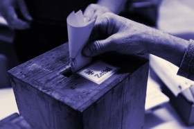 mano che mette una scheda in un urna elettorale