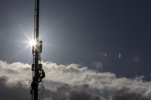 Un uomo su un antenna della telecomunicazione, sopra le nuvole.