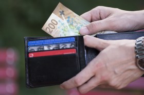 Una persona prelevare dal proprio portafoglio una banconota da 200 franchi.