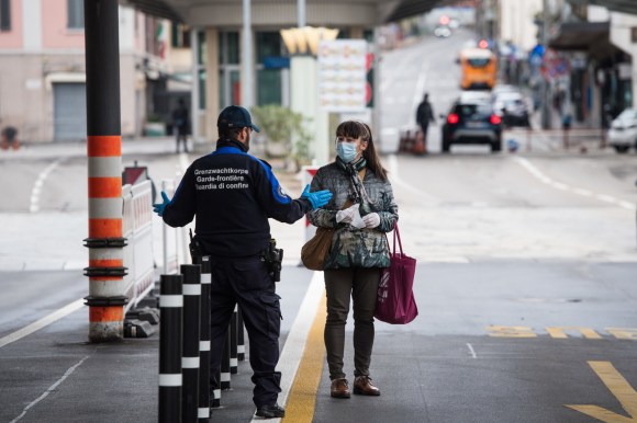 Una guardia di confine ferma una donna con la mascherina