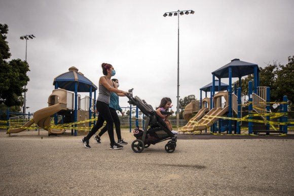 Due madri con passeggini in un parco con tutti i giochi sbarrati da nastro adesivo