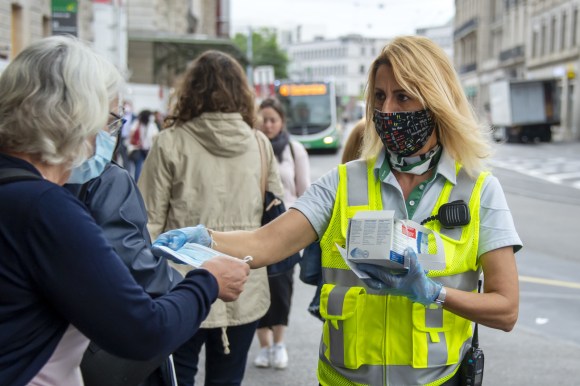 Una dipendente dei mezzi pubblici di Basilea distribuisce gratuitamente le mascherine.
