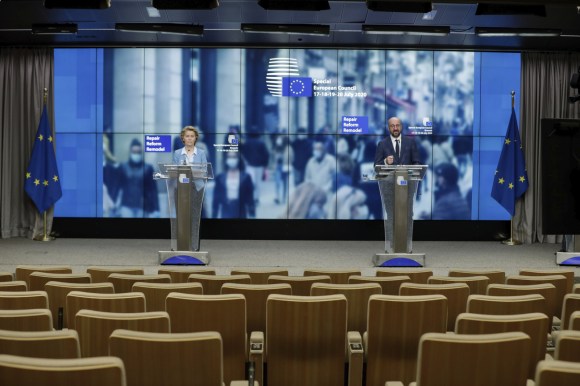 Usrula Von Der Leyen e Charles Michel a due pulpiti di fronte a sedie vuote di sala stampa; sul fondo loghi UE