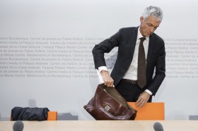 un uomo in completo giacca e cravatta posa una ventiquattr ore su una sedia.