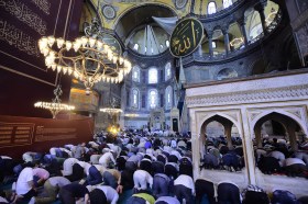 Interno di una moschea colma di uomini inginocchiati a testa china