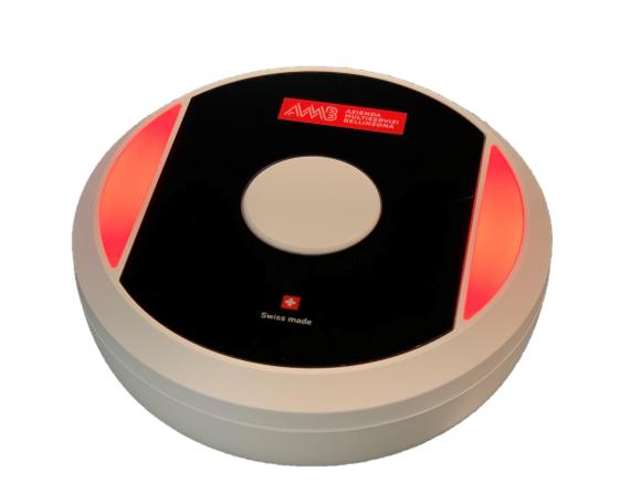 Disco di plastica bianca con spie luminose rosse e scritta AMB Aziende municipalizzate Bellinzona, posato su un tavolo di vetro