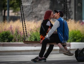 una giovane coppia che si bacia seduti su un altalena.