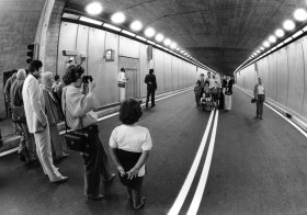 Famiglia posa nell interno di un tunnel stradale mentre qualcuno a fotografa; doppia linea sull asflato