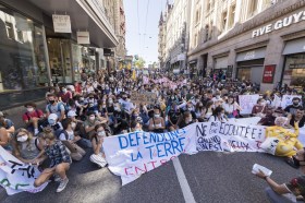 Giovani seduti in strada a scioperare a favore del clima: tutti con la mascherina sul volto.