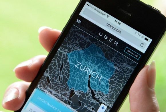 Primo piano di smartphone retto da mano femminile con app Uber aperta e cartina di Zurigo.
