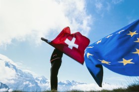 Sbandieratore si esibisce in ambiente alpino con bandiere della Svizzera e dell UE.