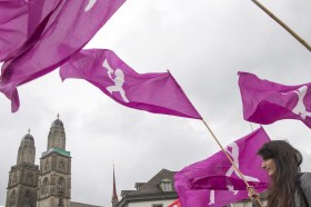 bandiere fucsia, simbolo della protesta femminile contro le disparità fra i sessi, che sventolano e sullo sfondo una cattedrale.