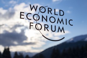 La scritta World economic forum su una porta che riflette le montagne e il cielo di Davos
