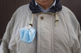 Person wearing jacket and mask tied to collar cords