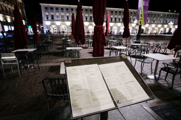 Primo piano di un leggio con un menu all esterno di un ristorante in una piazza di città con colonnato