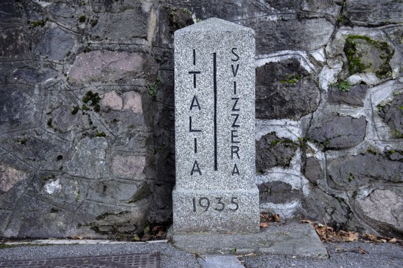Paracarro in pietra con scritte verticali Italia - Svizzera e linea di confine tra le due, data 1935