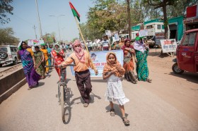 Piccolo corteo di dimostranti su strada indiana, in prima fila donne