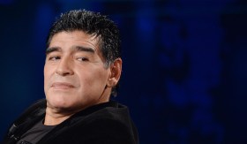 Primo piano di Maradona che guarda qualcuno di lato; sfondo blu scuro
