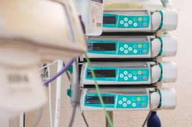 Quattro apparecchi elettronici accanto a letto d ospedale; si intravvedono tubicini e uno stetoscopio