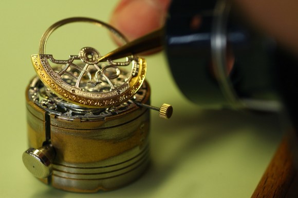 Artigiano che monta un componente di orologio