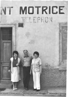 Due donne e un uomo posano davanti a uno stabile sul quale si intravede la scritta nt Motric - Telephon