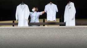Una operatrice sanitaria dal balcone dell ospedale civico di Lugano appende dei camici bianchi.