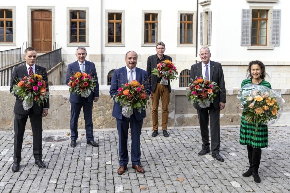 cinque uomini e una donna in piedi e con in mano un mazzo di fiori