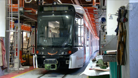 Convoglio ferroviario stile moderno tram in uno stabilimento con pedane sopraelevate e numerosi attrezzi