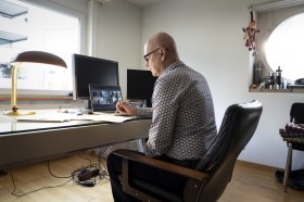 Un uomo alla scrivania di casa collegato in videochiamata su un tablet.