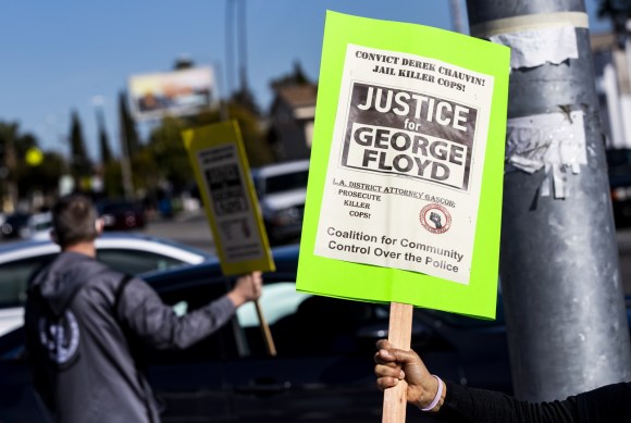 Un manifestante con un cartello scritto in inglese Giustizia per George Floyd.